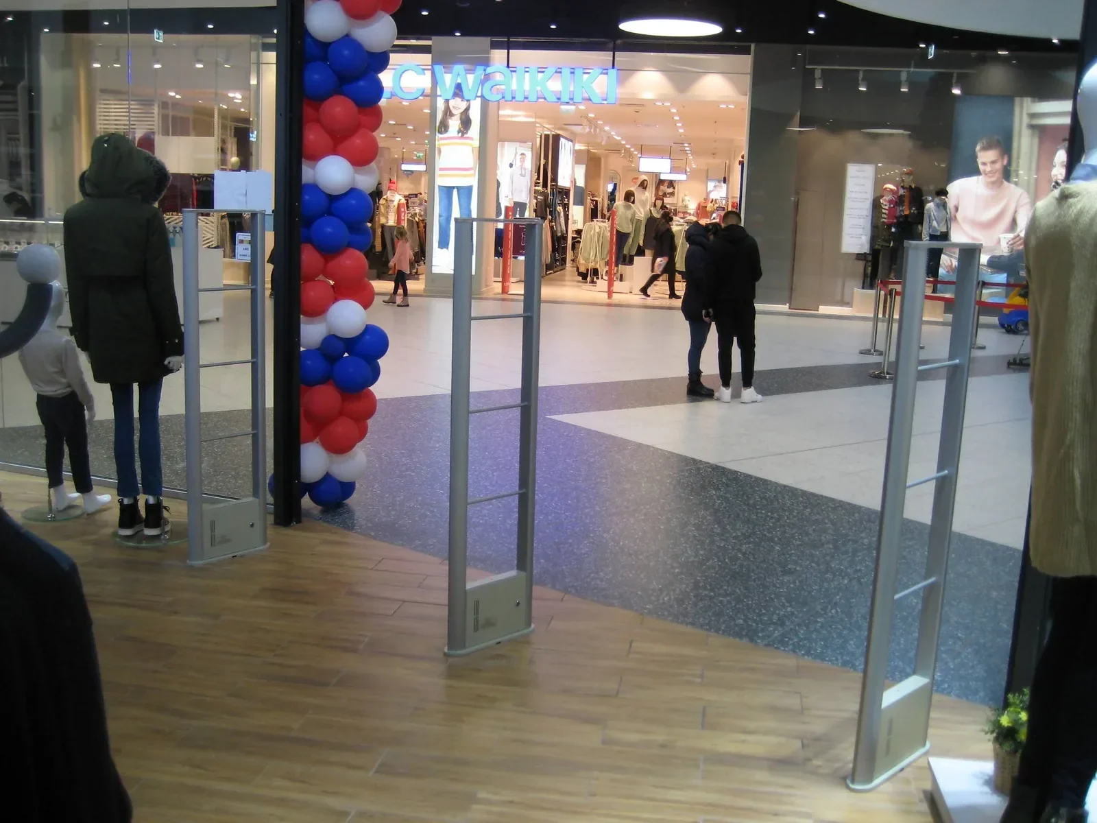 WELLPOINT anti-theft EAS gates at a shopping mall store entrance with shoppers