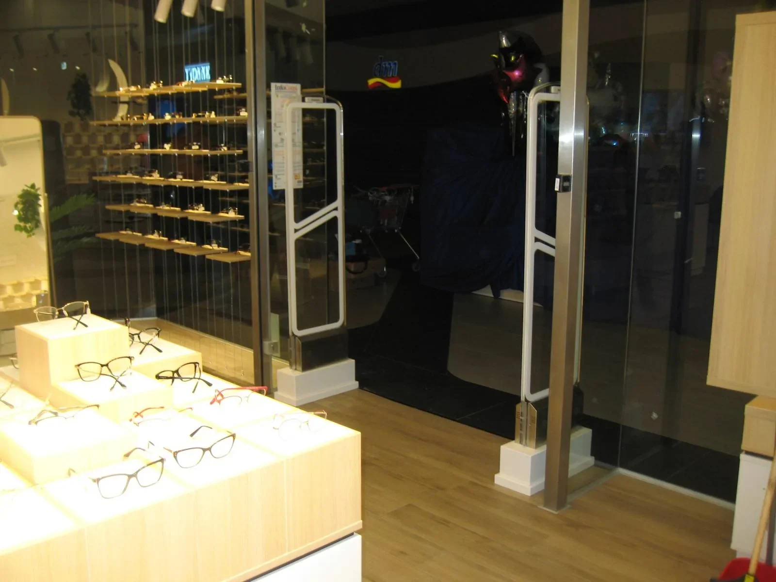 WELLPOINT slim anti-theft EAS pedestal pair at an optician entrance with eyewear displays